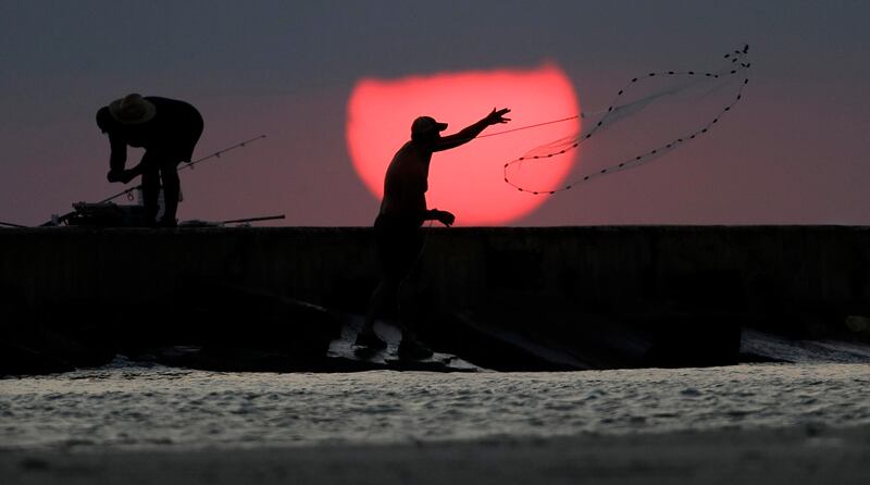 A fisherman casts his net along a jetty at sunrise in Port Aransas, Texas. The coastal bend area is still recovering from the effects of Hurricane Harvey. Eric Gay / AP Photo