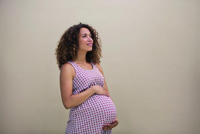 A pregnant woman holds her bump feeling positive on a clean background. (Getty Images)