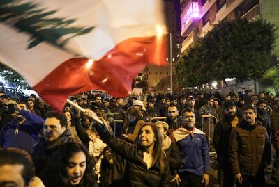 Lebanese protesters wave the national flag as they gather outside the house of Lebanon's new prime minister in the capital Beirut, calling for resignation less than 10 days after he was appointed, on December 28, 2019.  Protests continued after the resignation of the previous prime minister, while political parties negotiated for weeks before nominating Hassan Diab, a professor and former education minister, to replace him on December 19.  / AFP / ANWAR AMRO
