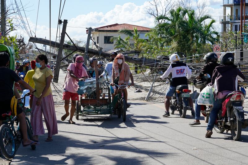 Cebu residents pass electrical posts toppled by Typhoon Rai. AP Photo
