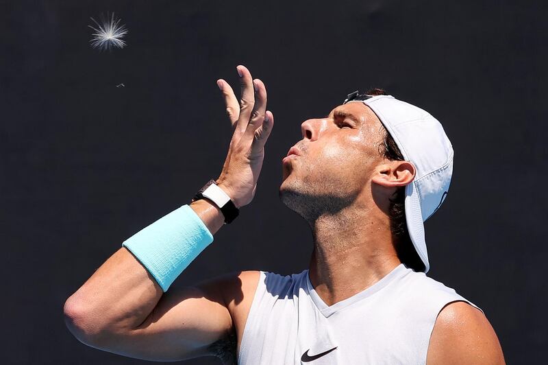 Spain's Rafael Nadal blows on a dandelion during a practice session  at Melbourne Park during the Australian Open tennis tournament in Melbourne on Wednesday, February 10. AFP