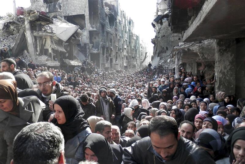 FILE - In this Jan. 31, 2014 file photo released by the United Nations Relief and Works Agency for Palestine Refugees, shows residents of the besieged Palestinian camp of Yarmouk, queuing to receive food supplies, in Damascus, Syria. Actors Hugh Grant and Viggo Mortensen are among more than 25 celebrities and public figures expressing "horror" over President Donald Trump's decision to cut funding to UNWRA. The group said in a joint statement Thursday, Jan. 25, 2018, that "the real target of this lethal attack is the Palestinian people themselves." (UNRWA via AP, File)