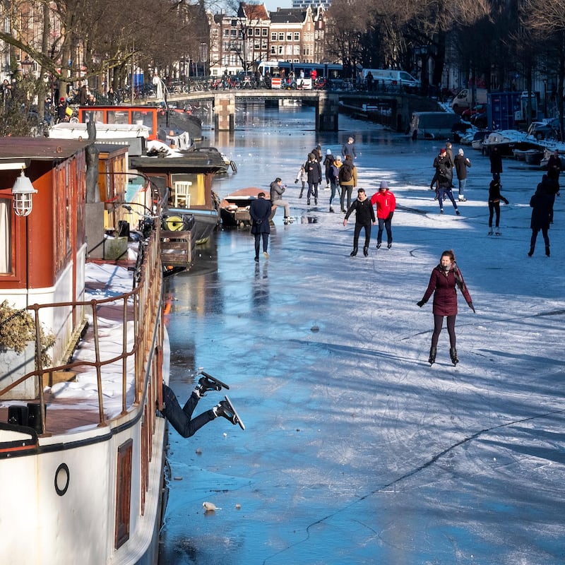 A skater dangles from a boat as dozens of skaters took to the frozen surface of Amsterdam's historic Prinsengracht canal in Amsterdam, Netherlands. AP