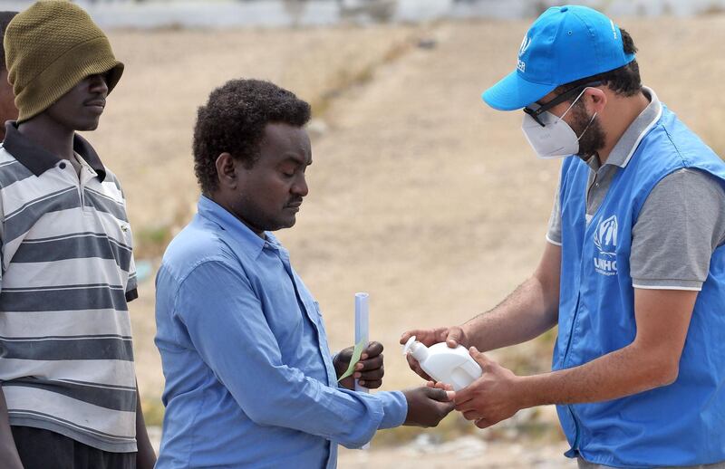 A man sanitises his hands against the coronavirus Covid-19 before collecting aid at a United Nations' High Commissioner for Refugees (UNHCR) camp for displaced Libyans and asylum seekers, on May 12, 2020 in the Libyan capital Tripoli during the Muslim holy month of Ramadan. / AFP / Mahmud TURKIA
