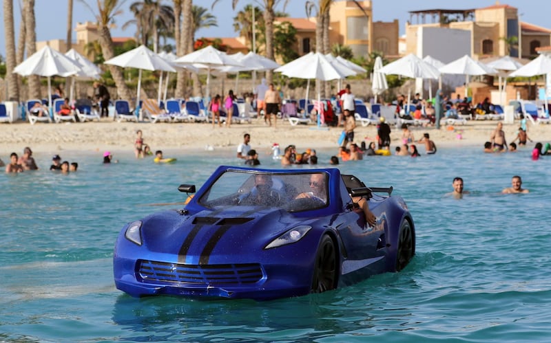 Karim Amin, one of the Egyptians who invented this vehicle that can drive on water, gives bathers at Porto Marina in Alexandria a closer look at the water car. Reuters