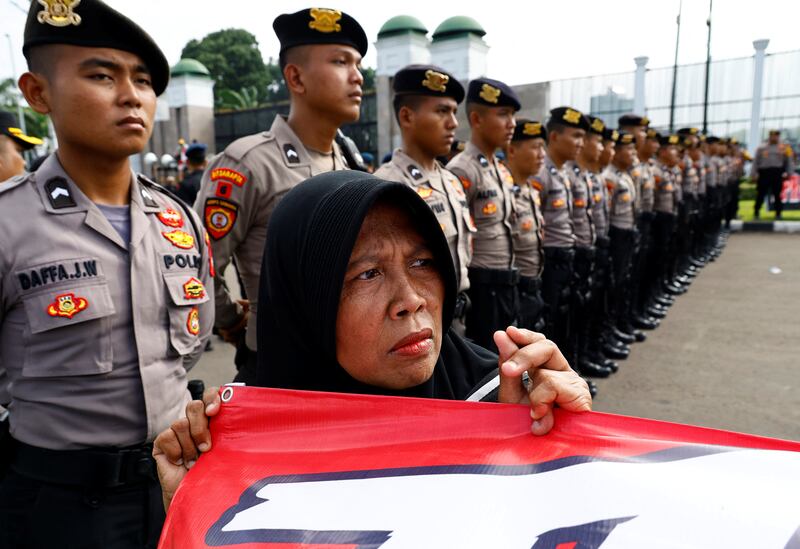 An anti-government protester stands in front of police officers during a rally demanding a fair election, outside the Indonesian Parliament in Jakarta. Reuters