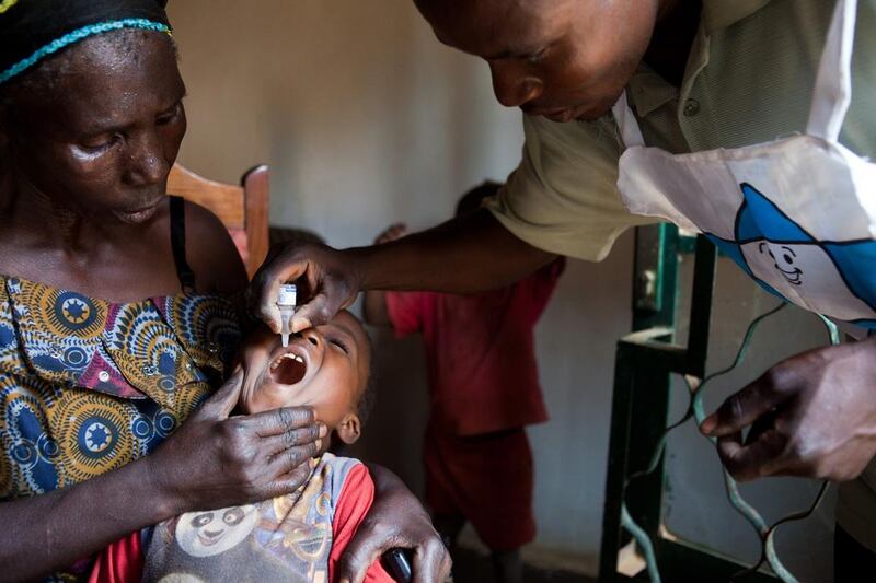 A Democratic Republic of Congo (DRC) Ministry of Health employee (right) administers a polio vaccination to a congolese child during the first day of a national polio mass immunisation campaign in Lubumbashi. AFP
