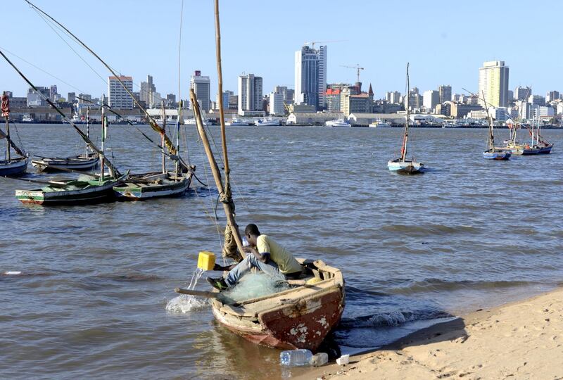 FILE PHOTO: A fisherman cleans his boat beneath Maputo's skyline, Mozambique, August 15, 2015. REUTERS/Grant Lee Neuenburg/File Photo