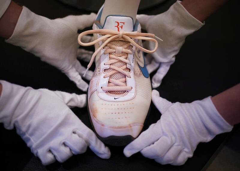 Christie's technicians handle a signed Nike sneaker which is part of Swiss tennis player Roger Federer's champion kit worn at the French Open, 2009.