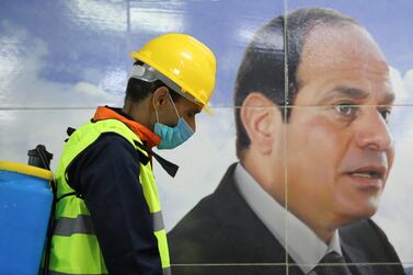 A sanitation worker sprays disinfectant beside a poster of Egyptian President Abdel Fattah El Sisi at Al Shohadaa metro station in Cairo on March 22, 2020. Reuters