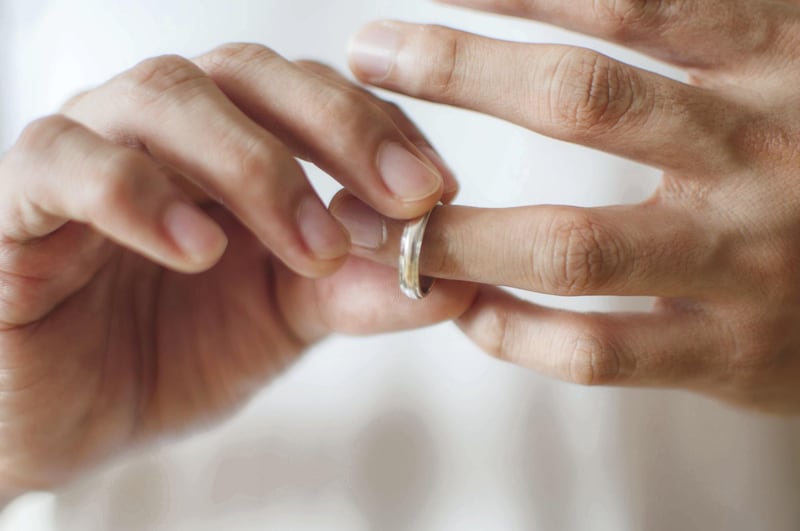 A close-up view of a young man's hands removing his wedding ring a concept of relationship difficulties