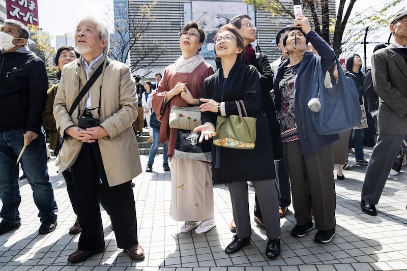 People react as they watch a news broadcast of Japan's Chief Cabinet Secretary Yoshihide Suga unveiling the name of Japan's next imperial era. Bloomberg
