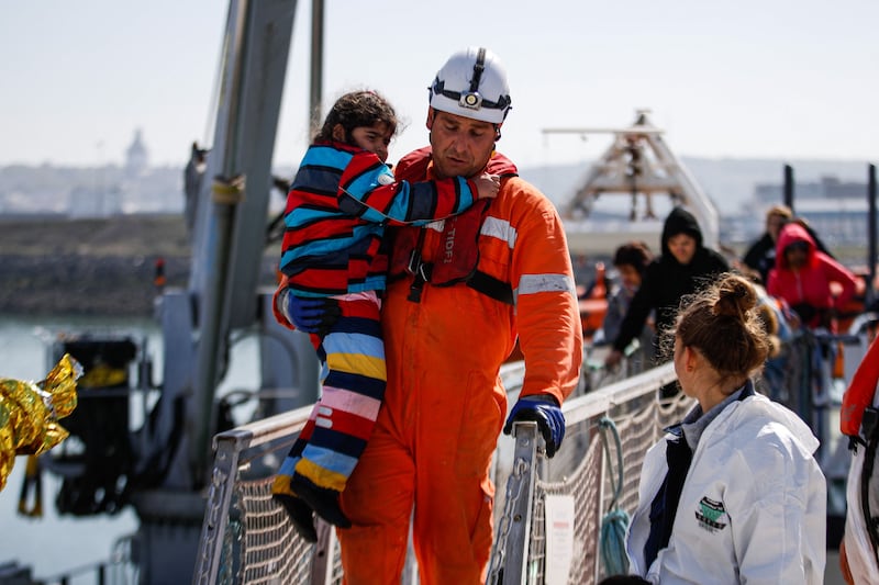 A rescuer carries a child as they disembark from the 'Abeille Languedoc'. 