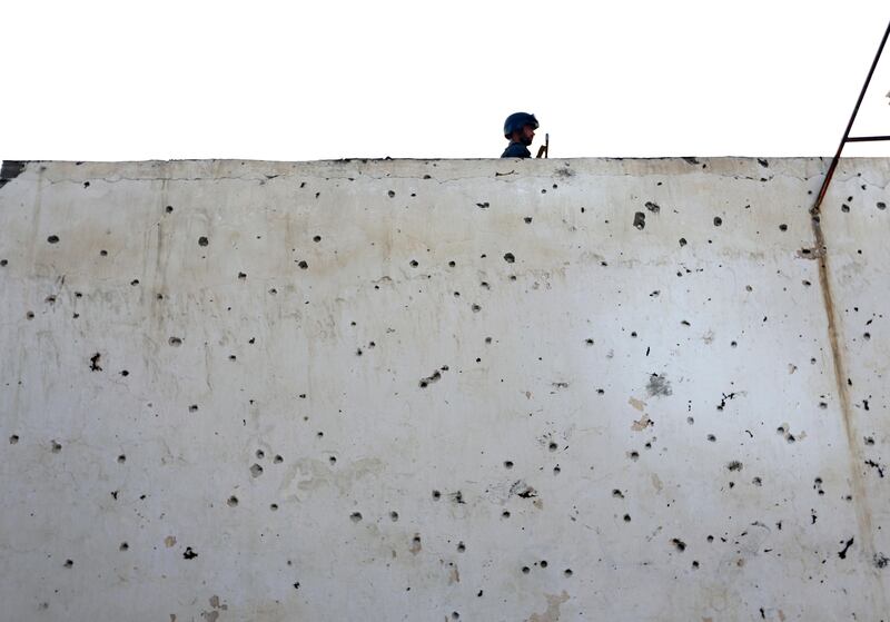 An Afghan police officer stands guard on a bullet ridden wall at a Shiite mosque where gunmen attacked during Friday prayers, in Kabul. Rahmat Gul / AP Photo
