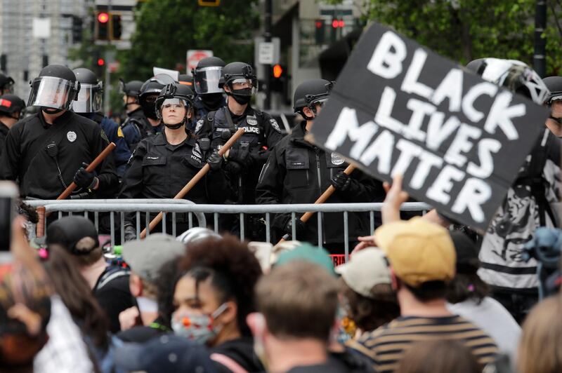Police officers behind a barricade look on as protesters fill the street in front of Seattle City Hall. AP Photo