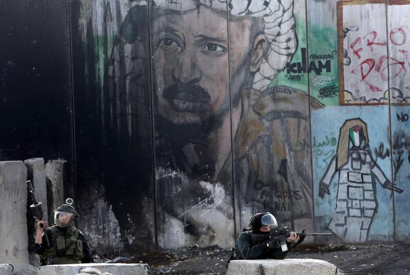 The image of former Palestinian president Yasser Arafat looks over Israeli security forces near Ramallah. Israel is trying to paint Mahmoud Abbas as another Arafat. Photo: Abbas Momani / AFP