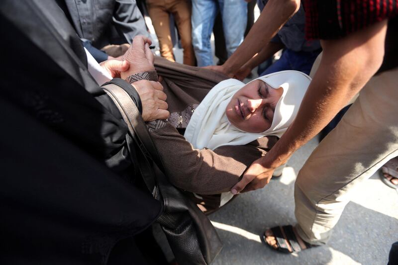 A Palestinian woman is helped after falling to the ground during an attempt to block a UN convoy, including the Secretary-General Antonio Guterres, at the Erez crossing in the northern Gaza Strip. Ibraheem Abu Mustafa / Reuters
