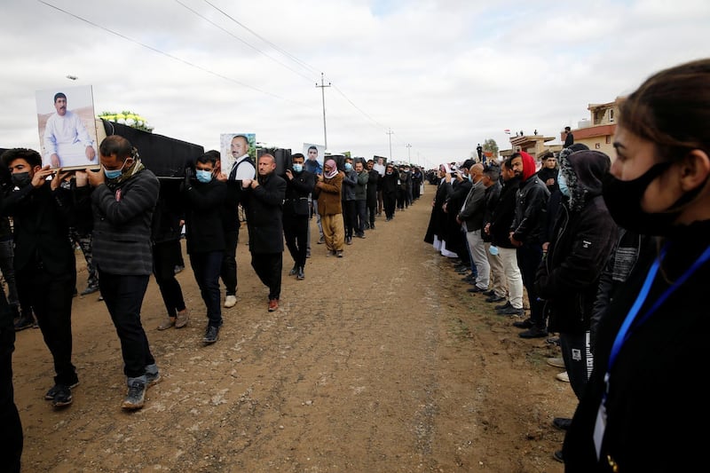 Mourners carry remains of people from the minority Yazidi sect, who were killed by Islamic State militants, after they were exhumed from a mass grave, to bury them in Kojo, Iraq February 6, 2021. REUTERS/Thaier al-Sudani