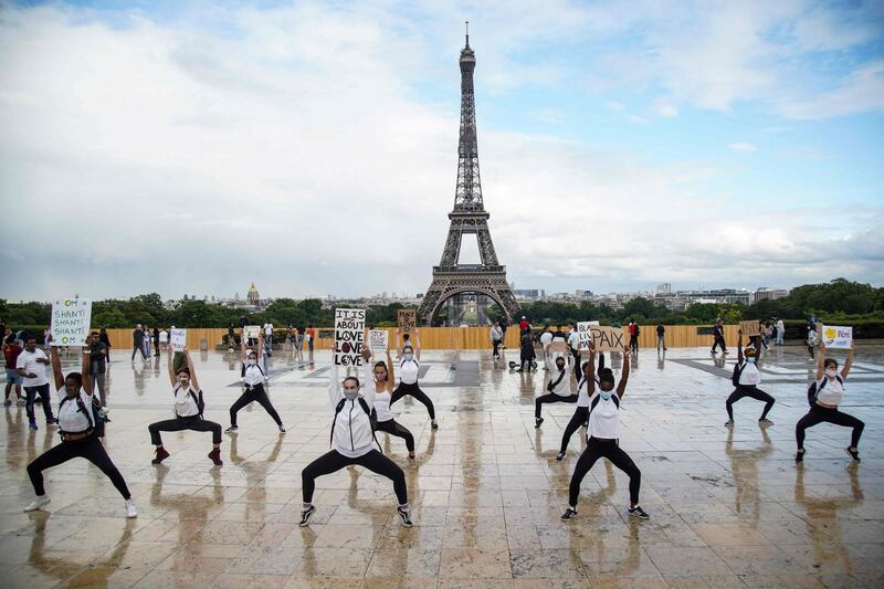 Members of Hermine Prunier's yoga group hold up placards as they perform a choreography to an Indian song for world peace and protest to show their support for the Black Lives Matter movement on the Parvis des droits de l'homme, place du Trocadero, in Paris, during the French Festival of Music.  AFP