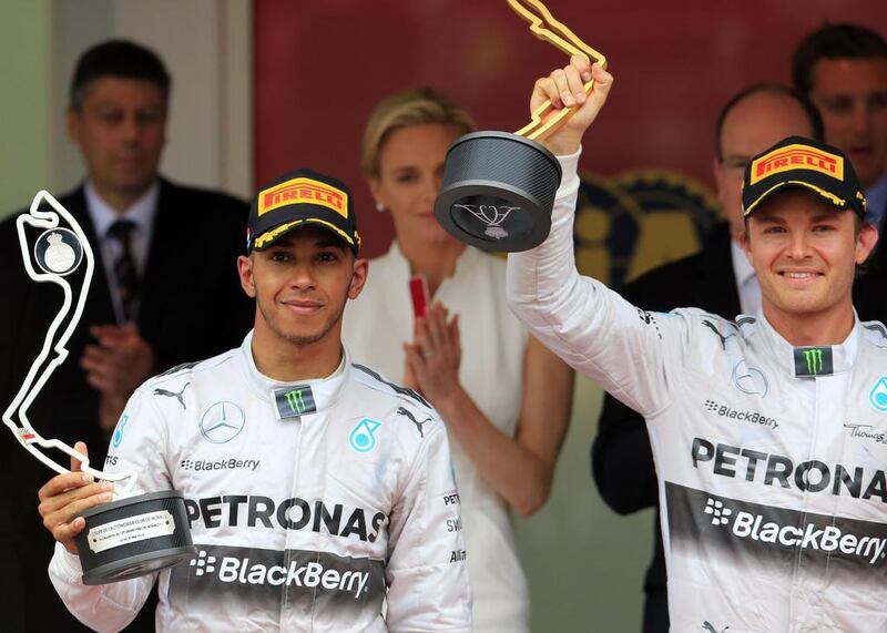 Mercedes' German driver  Nico Rosberg, right, holds his trophy next to Mercedes' British driver Lewis Hamilton on the podium of the Monaco street circuit after winning the Monaco Formula One Grand Prix in Monte Carlo on May 25, 2014. AFP PHOTO / ALEXANDER KLEIN

