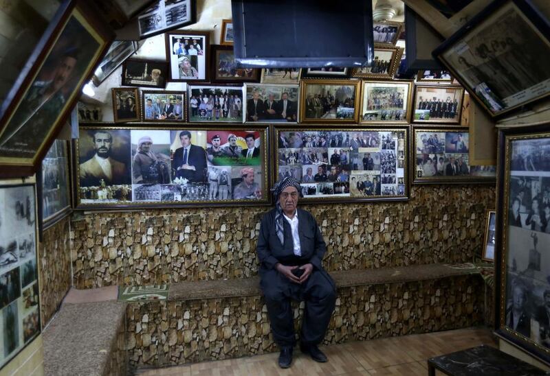 Iraqi Khalil Salih poses in his cafe where almost every inch of his cafe in northern Iraq is covered with photographs that tell the county's history. Safin Hamed / AFP  