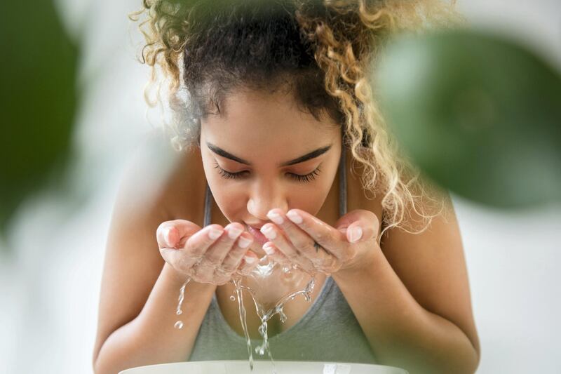 Mixed Race woman splashing water on face