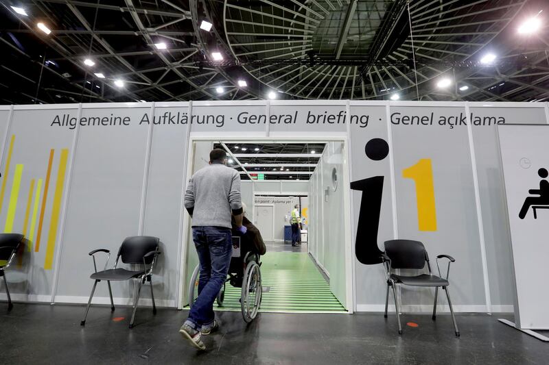 A person in a wheelchair is guided in a new coronavirus vaccination center at the 'Velodrom' stadium in Berlin, Germany. EPA