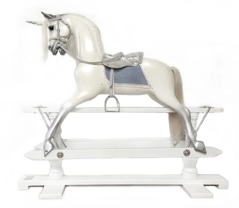 A rocking horse from Children's Lane takes the form of a unicorn, in pearlescent paint with silver details and a blue-grey blanket, mounted on a white oak base. Courtesy Children's Lane