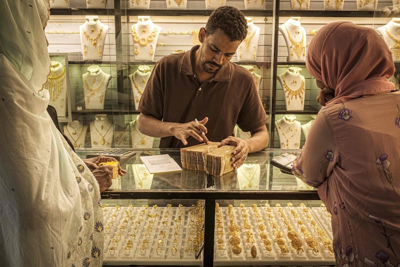 TOPSHOT - A jeweller counts stacks of Sudanese twenty pound bills at a shop in the capital Khartoum's gold market in its downtown district on June 20, 2019. Shops selling gold in downtown Khartoum's famous gold market have reopened in recent days after they were largely shut earlier this month as part of an overall civil disobedience campaign launched by protest leaders in the wake of a deadly crackdown on demonstrators. / AFP / Yasuyoshi CHIBA
