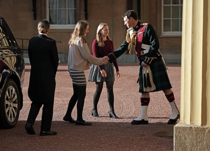Ms Truss's daughters Frances and Liberty are greeted by King Charles's equerry Lt Col Johnny Thompson at Buckingham Palace. PA