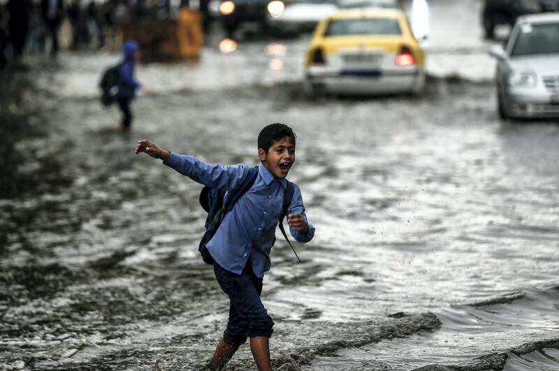 A young pupil crosses a flooded street during heavy rain in Gaza City on November 10, 2018. (Photo by MAHMUD HAMS / AFP)