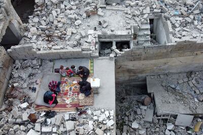 This picture taken on May 4, 2020 during the Muslim holy fasting month of Ramadan shows an aerial view of members of the displaced Syrian family of Tariq Abu Ziad, from the town of Ariha in the southern countryside of the Idlib province, breaking their fast together for the sunset "iftar" meal, in the midst of the rubble of their destroyed home upon their return to the town after fleeing during the previous military assault on the town by Syrian government forces and their allies.  / AFP / Aaref WATAD
