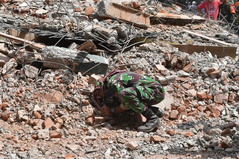 An Indonesian soldier taking part in search and rescue operations looks for earthquake victims in the rubble in Tanjung on Lombok island.  AFP