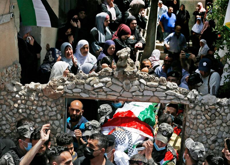 Relatives of Ahmed Daraghmeh, a member of Palestinian intelligence services who was killed by Israeli forces the previous day at the Zaatara (Tapuach) junction south of Nablus in the occupied West Bank, look on as his body passes below during a funerary procession in the town of al-Lubban al-Sharqiya near Nablus on May 12, 2021. Daraghmeh, 30, was killed and another Palestinian wounded by Israeli army gunfire in the north of the occupied West Bank as violence soared between Israel and the Palestinian territories. Both were shot at an Israeli army checkpoint near Nablus. The Israeli army earlier reported an "attempted drive-by shooting at Tapuah Junction" near Nablus. / AFP / ABBAS MOMANI
