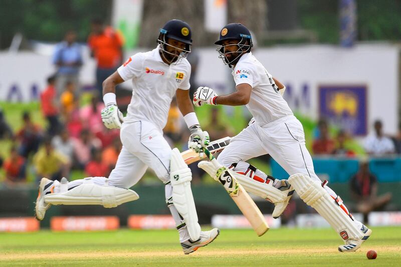 Sri Lankan cricket captain Dimuth Karunaratne (L) and Lahiru Thirimanne runs between the wickets during the fourth day of the opening Test cricket match between Sri Lanka and New Zealand at the Galle International Cricket Stadium in Galle on August 17, 2019. / AFP / ISHARA S. KODIKARA
