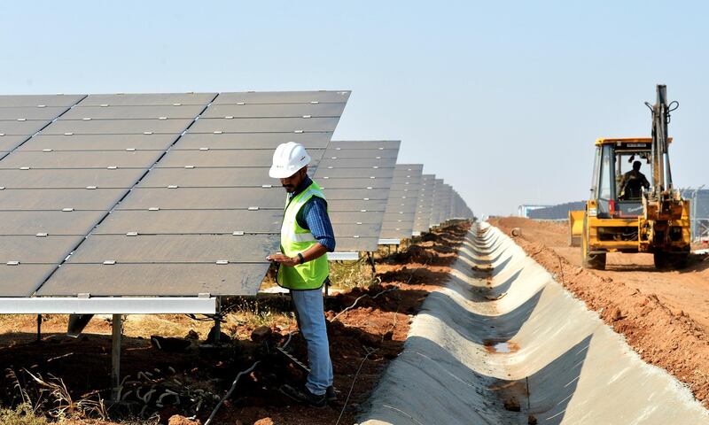 An Indian worker conducts routine checks of solar panels at "Shakti Sthala", the 2000 Megawatt solar power park in Pavagada Taluk, situated about 150 kms from Bangalore on March 1, 2018. - The 1st phase of Shakti Sthala, which was inaugurated today is coming up in an area of 13,000 acres with an investment of 165,000 million rupees by the time of its completion is said to be the world's largest solar park. (Photo by MANJUNATH KIRAN / AFP)