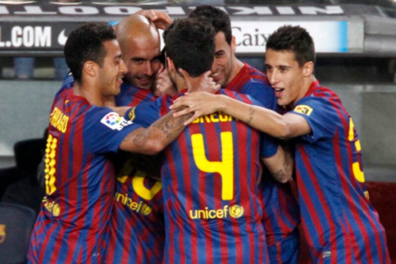 Barcelona's Lionel Messi (obscured) celebrates his fourth goal with coach Pep Guardiola (2nd L) and team mates against Espanyol during their Spanish first division soccer match at Nou Camp stadium in Barcelona May 5, 2012.     REUTERS/Gustau Nacarino  (SPAIN - Tags: SPORT SOCCER)