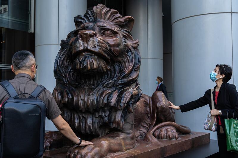 People touch a statue of a lion in front of the HSBC Holdings Plc headquarters building in Hong Kong. Bloomberg