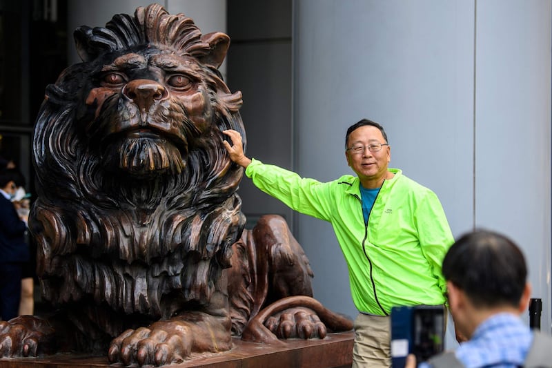 A man poses for a photo next to a lion statue outside HSBC bank headquarters building in Hong Kong. AFP