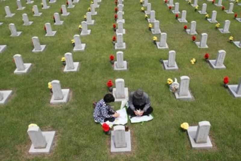 Lee Young-sil (L), 61, and her husband Song Seok-won, 64, mourn in front of the gravestone of her father Lee Bae-geun, a soldier who died in 1952 during the 1950-53 Korean War, at the National Cemetery in Seoul to mark the 60th anniversary of the outbreak of the war June 25, 2010. North Korea has issued a no-sail warning off the west coast of the Korean Peninsula in what South Korean officials said on Friday was likely part of routine military drills, amid heightened antagonism between the rivals. REUTERS/Truth Leem (SOUTH KOREA - Tags: POLITICS ANNIVERSARY IMAGES OF THE DAY) *** Local Caption ***  SEO201_KOREA-NORTH-_0625_11.JPG