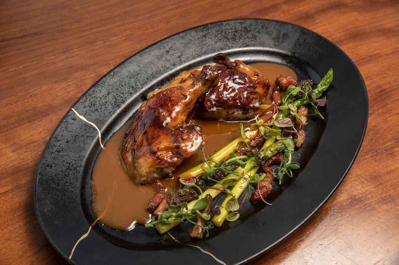 The roasted half chicken is stuffed with garlic butter and served with an asparagus ragout and French morels