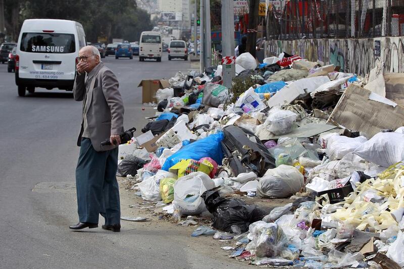 A Lebanese man covers his nose from the smell as he passes by a pile of garbage on a street in Beirut. Bilal Hussein / AP Photo