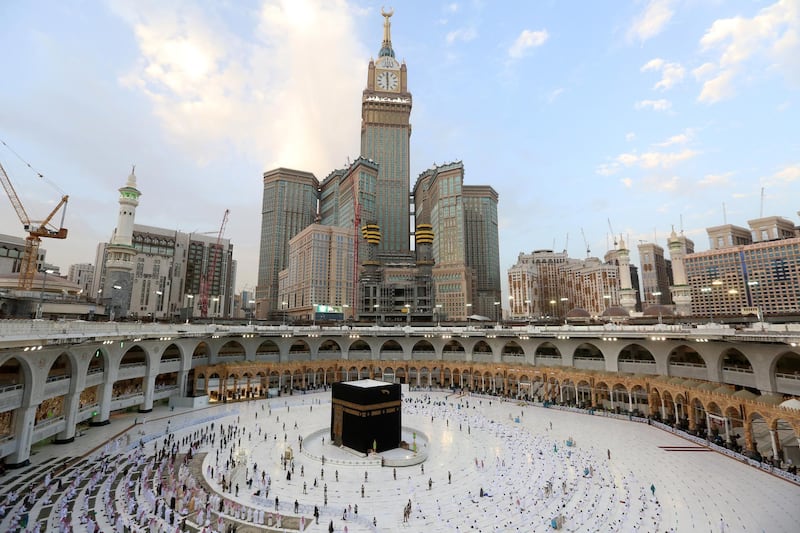 Muslim worshippers gather to pray around the Kaaba, the holiest shrine in the Grand Mosque complex in Saudi Arabia's holy city of Mecca, to mark the end of the fasting month of Ramadan, on May 13, 2021, while in the background looms the Abraj al-Bait skyscraper complex housing the Mecca Royal Clock Tower. (Photo by Abdulghani ESSA / AFP)