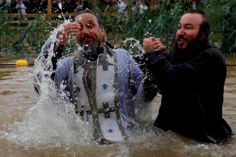 A Russian Christian Orthodox priest baptises a pilgrim in the muddy waters of the Jordan River during the Epiphany celebrations at the Qasr al- Yahud baptismal site near the West Bank city of Jericho. AFP