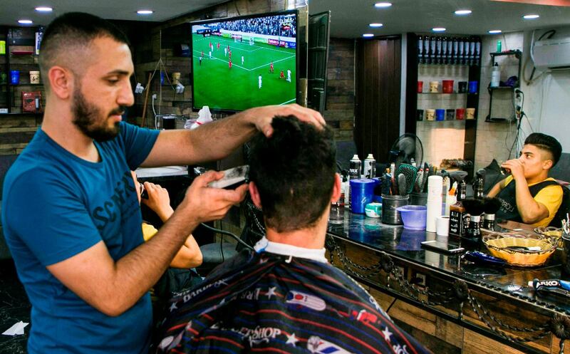 A barber cuts the hair of a Palestinian youth watching the World Cup 2022 Asian qualifying match. AFP