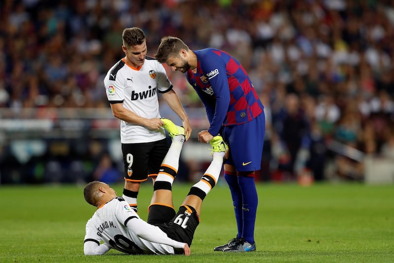 Barcelona's Gerard Pique helps Valencia's Kevin Gameiro stretch. EPA