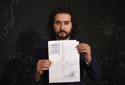 In this photo taken on October 8, 2018, Afghan co-founder and president of ArtLords Omaid Sharifi, 32, poses for a picture as he holds his id card or Tazkira registered to vote in the upcoming parliamentary election, in Kabul. Bloody violence has forced thousands of polling centres to close and stopped millions of people from registering to vote. But war-torn Afghanistan's long-delayed legislative election will still go ahead on October 20, officials say. Almost nine million people are eligible to vote in the ballot, which is more than three years late and largely funded by the international community.
 / AFP / WAKIL KOHSAR
