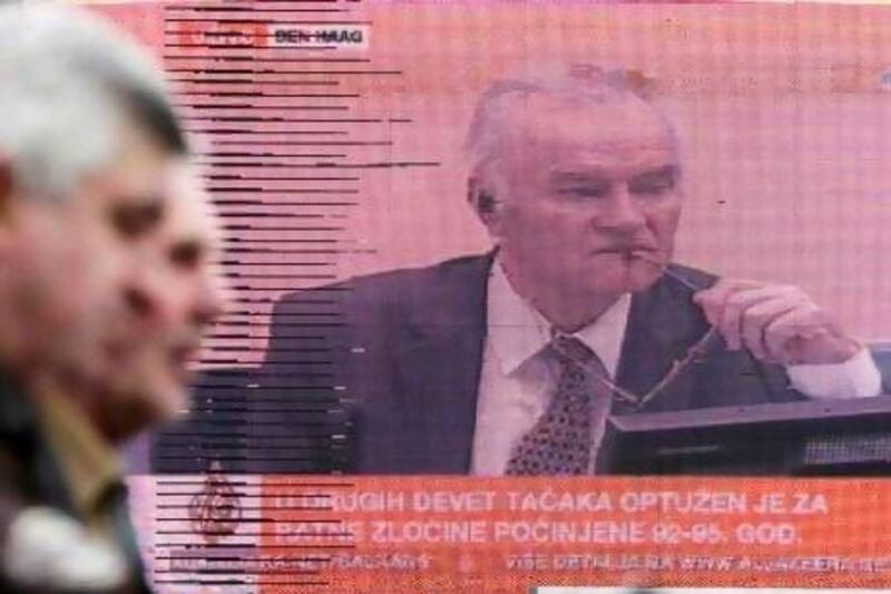Bosnians in Sarajevo pass a television screen showing a live broadcast of the trial of the Bosnian Serb General Ratko Mladic at the UN's Yugoslav war crimes tribunal in The Hague, Netherlands.