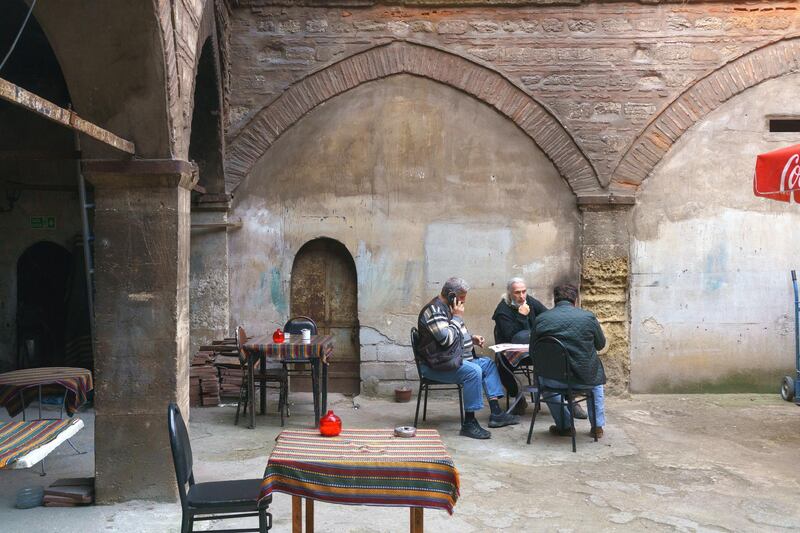 Turkish people drinking tea. 18th century building, “Corlulu Ali Pasha” inn-yard in the Küçükpazar district in Istanbul.

The courtyard is entered by passing through the arched door and passage on the street of Kucukpazar, Istanbul. Istanbul, Turkey 2021