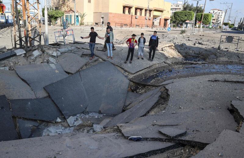 Palestinian youths take pictures with their smart phones of a huge crater on a main road in Gaza City following continued Israeli airstrikes overnight on the Hamas-controlled Gaza Strip. AFP